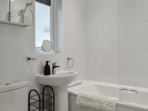 y baño blanco con lavabo y bañera. en Anchor Cottage, en Portpatrick