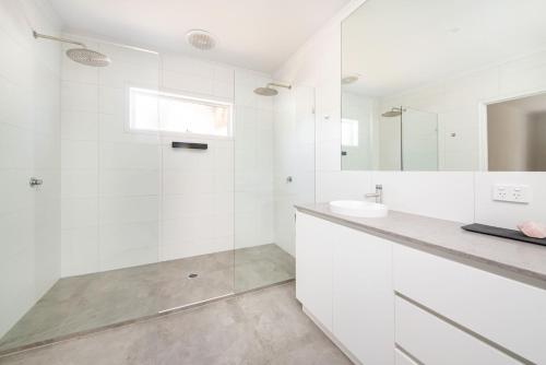 a white bathroom with a sink and a shower at Malibu in Mt Martha with solar heated pool in Mount Martha
