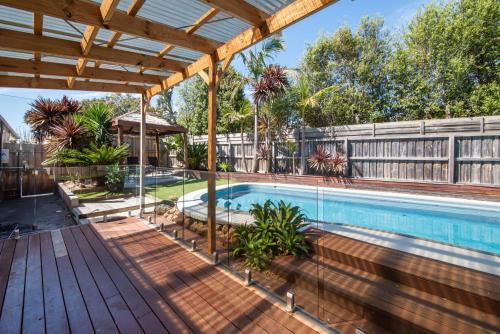 an outdoor swimming pool with a wooden pergola at Malibu in Mt Martha with solar heated pool in Mount Martha