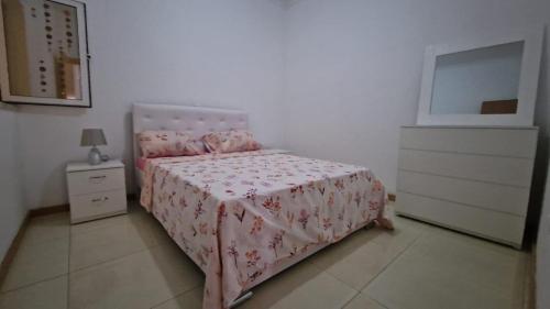 a bedroom with a bed with a pink bedspread and a dresser at Casa de férias com 2 quartos ou aluguer diária in Praia