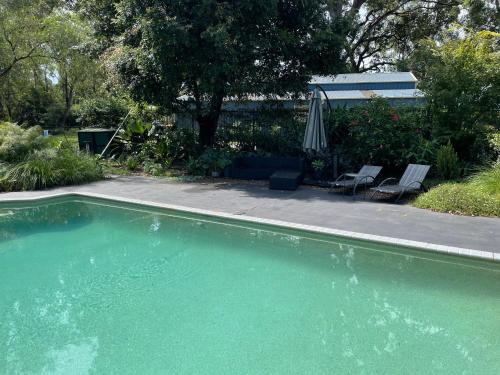 a swimming pool with two chairs and an umbrella at Haven Hideaway in Berry