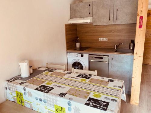 une petite cuisine avec une table et une cuisinière dans l'établissement Duplex au cœur du village avec balcon et garage à La Clusaz, proche des pistes et commodités - FR-1-459-216, à La Clusaz