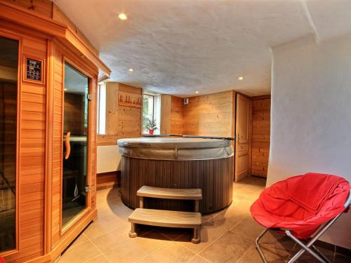 La grande salle de bains est pourvue d'une baignoire et d'un fauteuil rouge. dans l'établissement Chalet 12 pers avec sauna, jacuzzi, wifi, parking, animaux admis - FR-1-455-238, à La Plagne Tarentaise