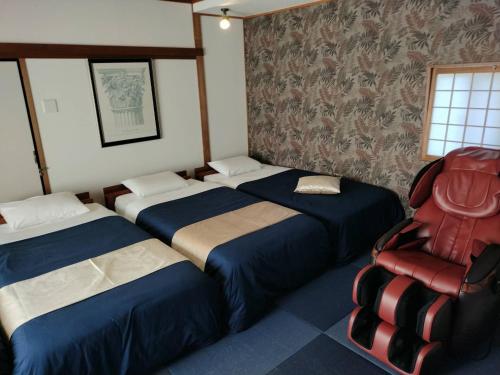 una habitación con 3 camas y una silla. en Villa Ortigia en Minamiawaji