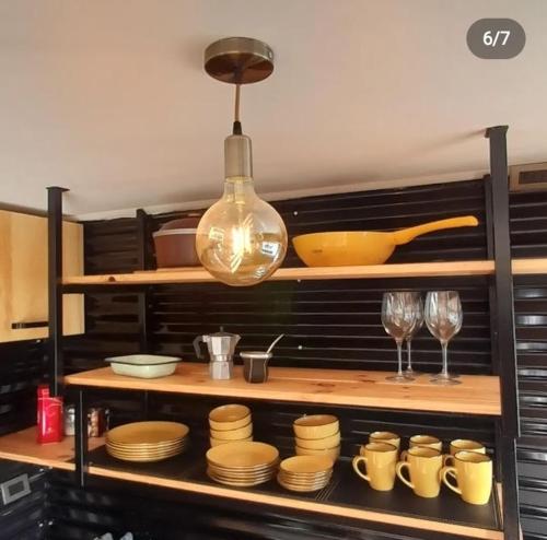 una cucina con piatti e bicchieri e una luce a ciondolo di Cabaña / loft a Puerto Montt
