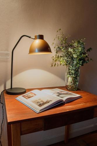 a table with a lamp and a book and a vase of flowers at Hotel Auen Posada Andina in La Unión
