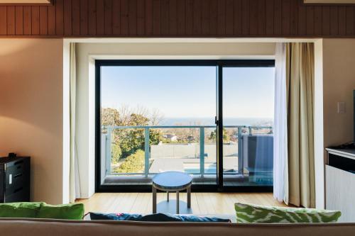 a living room with a couch and a large window at the salon 伊豆高原 Hotels & Resort in Ito