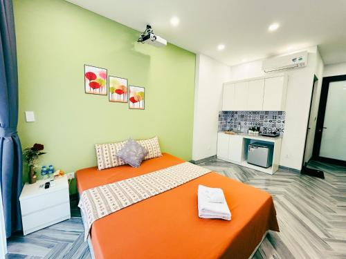 an orange bed in a room with a kitchen at Godidi Homestay&Apartment ( Westlake ) in Hanoi