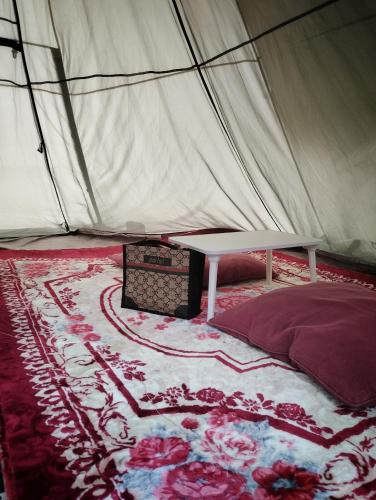 a tent with a bed and a table in it at AWANAZ FARM GLAMPING in Jitra