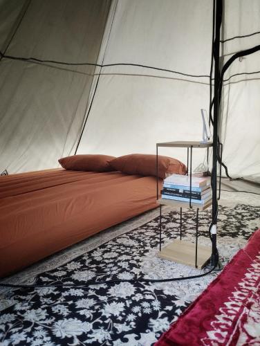 a bed in a tent with a side table at AWANAZ FARM GLAMPING in Jitra