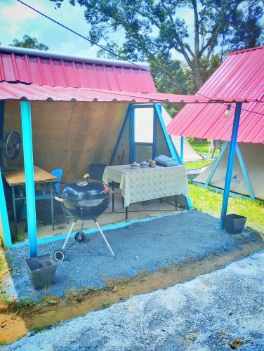 a grill and a table in a tent at AWANAZ FARM GLAMPING in Jitra