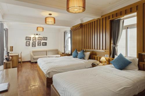 a hotel room with two beds and a couch at Hanoi Central Park Hotel in Hanoi