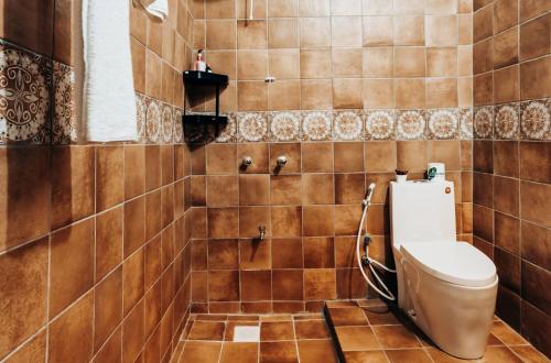 ein Bad mit einem WC und einer gefliesten Wand in der Unterkunft Safariland Home stay in Arusha