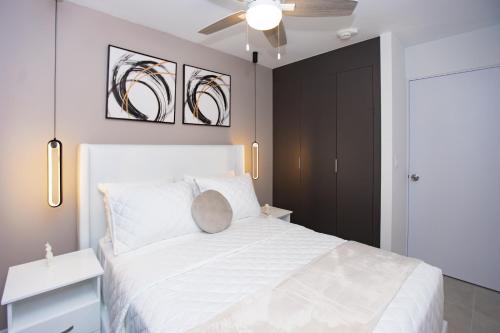 1 dormitorio con 1 cama blanca y ventilador de techo en Exclusivo apartamento piso 23, Sky Garden, en San José