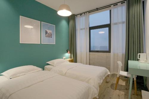 1 dormitorio con 2 camas, escritorio y ventana en Swan's Journey International Youth Hostel - Changsha Wuyi Square IFS IFC, en Changsha