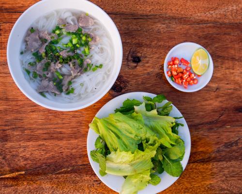 stół z talerzami jedzenia i miską makaronu i sałatki w obiekcie Then Pa village w mieście Loung Co