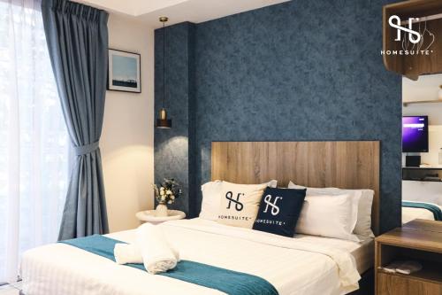 a bedroom with two beds and a blue wall at Homesuite' Home at Aeropod SOVO in Kota Kinabalu