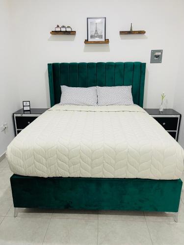 a bed with a green headboard and a white mattress at InDomus Rooms in Bacurimi