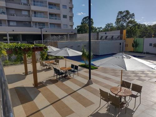 a patio with tables and chairs and umbrellas at Condomínio Recanto do Bosque- Flat Service in Caldas Novas