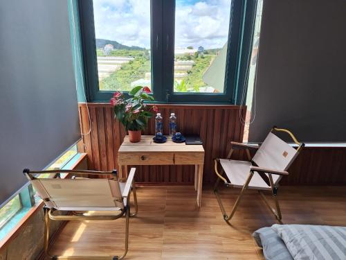 a room with two chairs and a table and two windows at Windy Home in Ấp Man Ling
