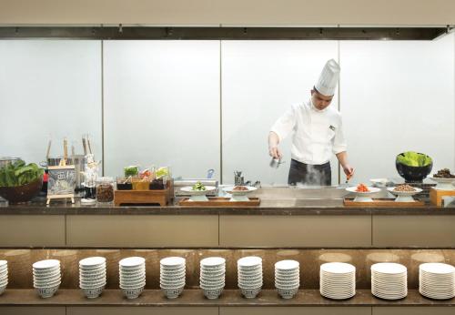 um chef de cozinha a preparar comida em Hamps Hotel ShenZhen em Shenzhen