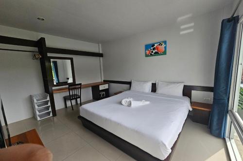 a bedroom with a white bed and a table and chair at The One Cozy Vacation Residence SHA Hotel in Chalong 