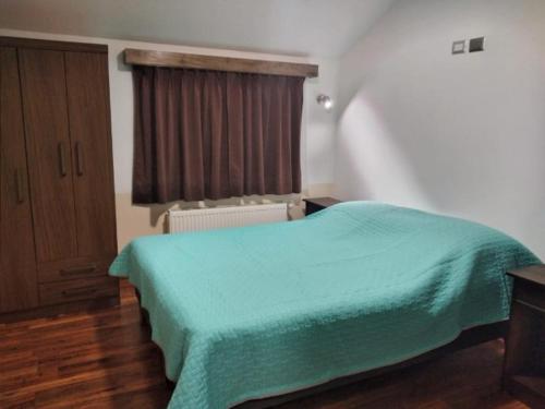 1 dormitorio con 1 cama con manta verde en Cabañas Angamos en Punta Arenas