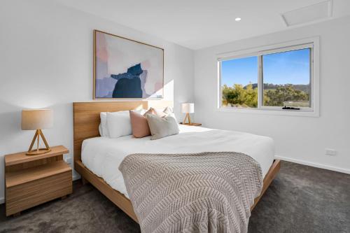 a white bedroom with a large bed and a window at Simply Stunning Holiday Views! in Legana