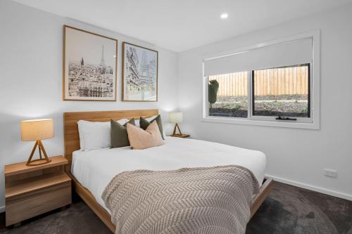 a white bedroom with a bed and two windows at Simply Stunning Holiday Views! in Legana