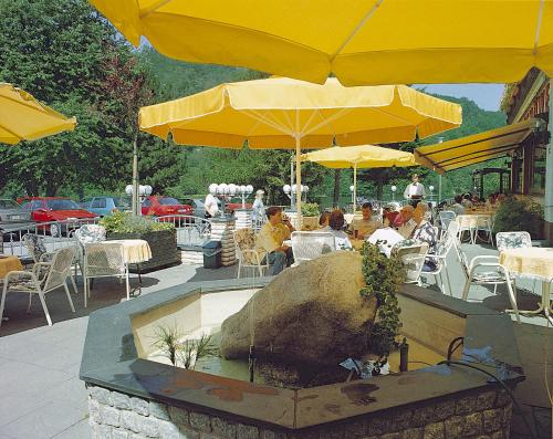 a group of people sitting at a restaurant under yellow umbrellas at Hotel Seemöwe in Simmerath