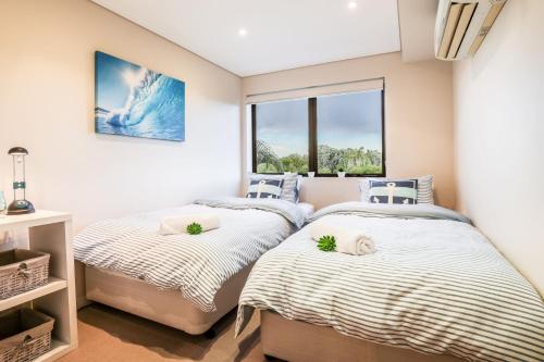 two twin beds in a room with a window at Loka 7 beachfront apartment in Agnes Water