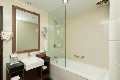 y baño con lavabo, ducha y espejo. en Swiss-Belinn Baloi Batam, en Nagoya