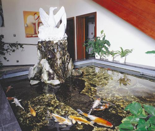 a fish pond with a white bird statue in a house at Hotel Seemöwe in Simmerath