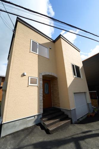 a yellow house with a staircase in front of it at THE LOBS, RUSUTSU in Kimobetsu