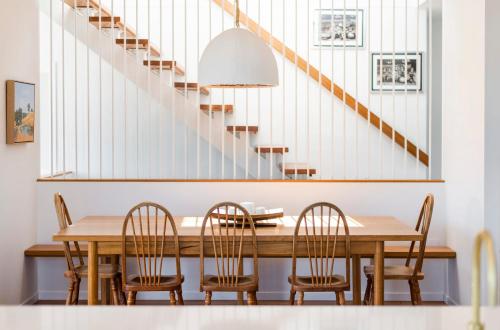 une salle à manger avec une table et des chaises et un escalier dans l'établissement Sandhurst - oceanstays, à Yamba