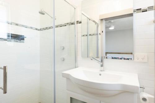 a white bathroom with a sink and a shower at Crystal Waters in Forster