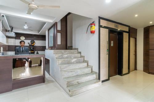 a staircase in a lobby with a man standing at a counter at Hotel Parkland Manage by G Express in Ahmedabad