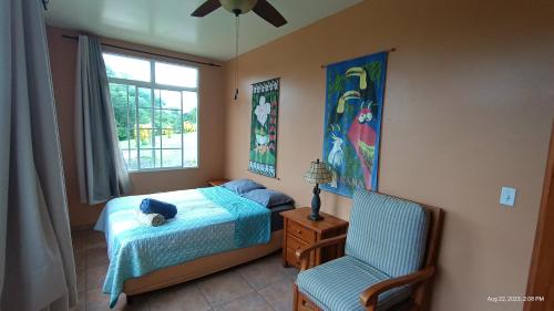 een slaapkamer met een bed, een stoel en een raam bij Boca Chica BnB at Gone Fishing Panama Resort in Boca Chica