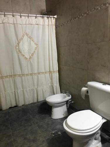 a bathroom with a toilet and a shower curtain at Casa La Loberia in La Lobería