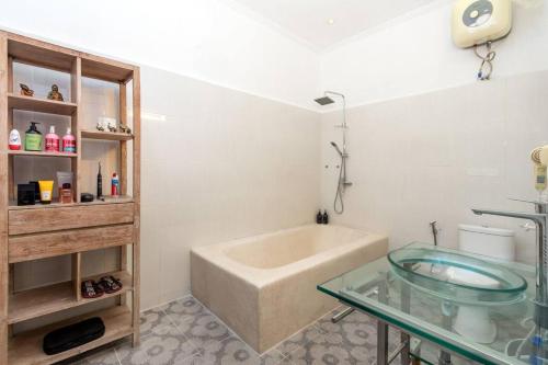 y baño con bañera y mesa de cristal. en Buddha Beach Villa Seminyak, en Seminyak