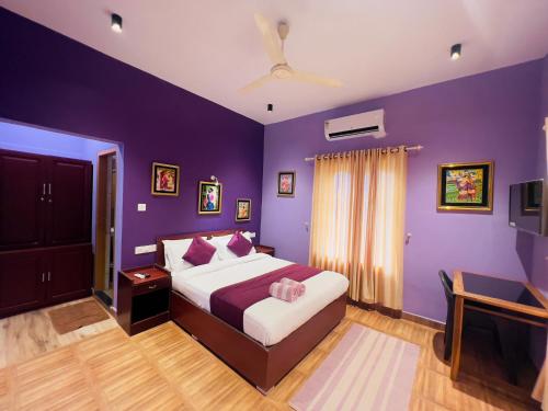 a bedroom with purple walls and a bed with pink pillows at Munnar Blue Mist in Munnar