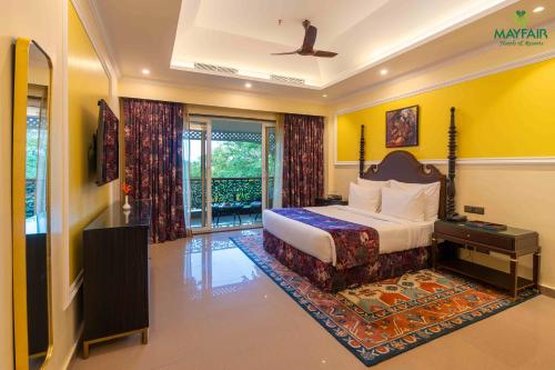 a bedroom with a king sized bed and a television at Mayfair Spring Valley Resort Guwahati in Guwahati