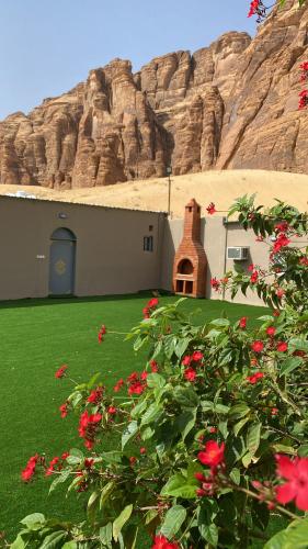 a building with red flowers in front of a mountain at الجوهرة Diamond plus in AlUla