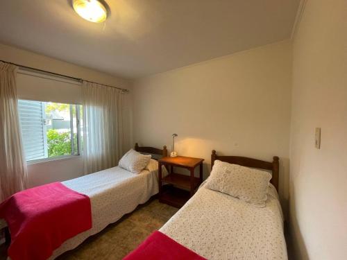 two beds in a room with a window at Casa Country Golf Club, Pagos en USD in Gualeguaychú