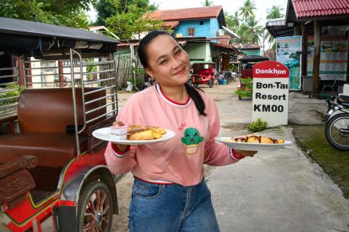 a woman is holding two plates of food at Bontai Resort, Don Khon in Ban Khon