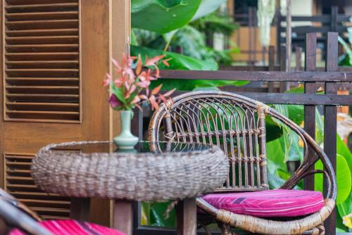 a rattan chair with pink cushions and a vase with flowers at Kanlaya's Eyrie, Luxury Homestay in Pang Mapha