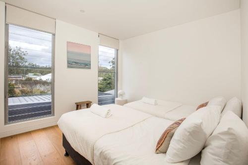 zwei Betten in einem weißen Zimmer mit Fenster in der Unterkunft Keppel - Pet Friendly - 4 Mins Walk to Beach in Huskisson