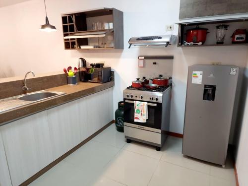 a small kitchen with a stove and a refrigerator at Departamento familiar en Huacachina in Ica