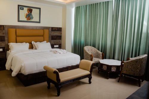 a bedroom with a bed and two chairs and a table at Hotel Grand Lotus in Dimāpur