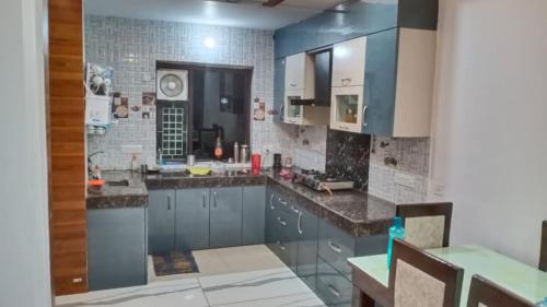 a kitchen with blue cabinets and a tile wall at Sindhu Villa in Lucknow